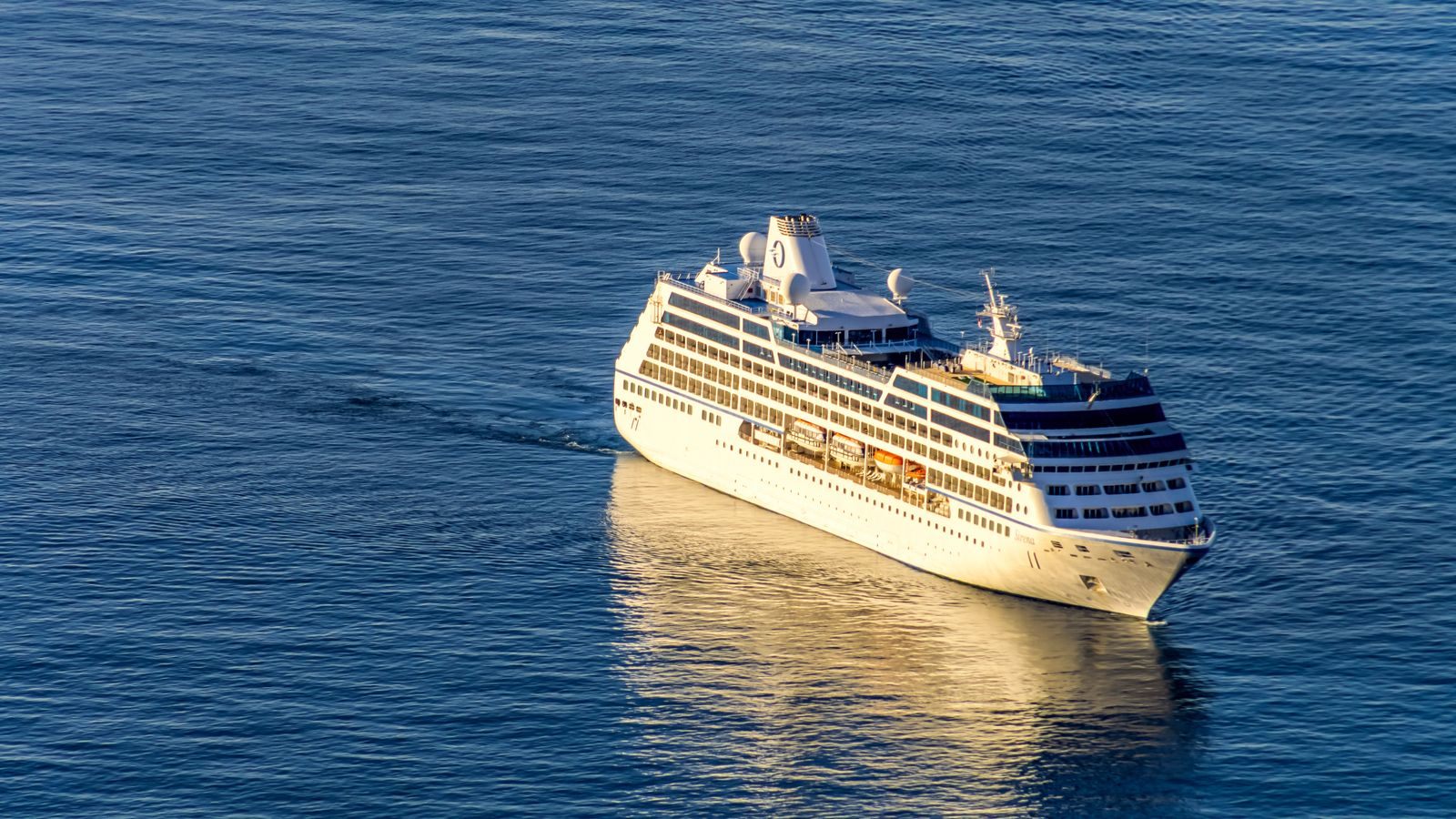 A small white luxury cruise ship sailing on a calm blue sea, the kind of voyage a luxury cruise consultant helps you choose