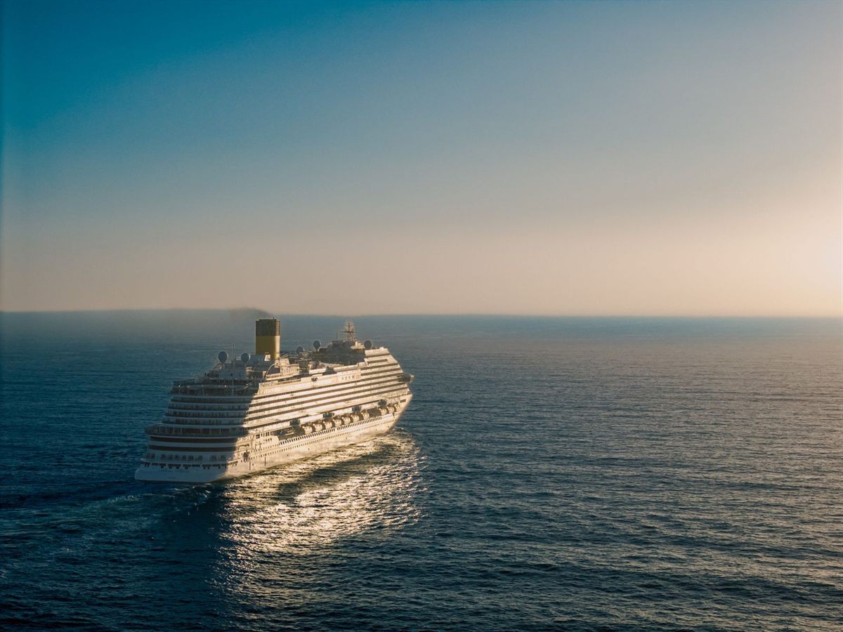 A cruise ship heading out across the open sea in soft evening light