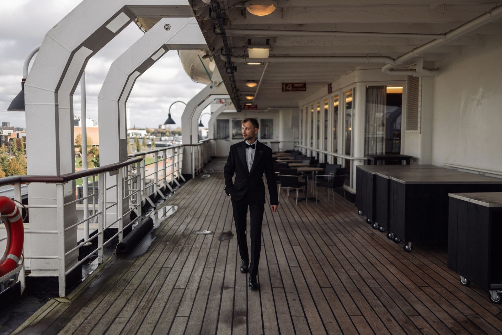 A man in a dinner jacket on the teak promenade deck of a classic ship, the setting luxury cruise travel agents sell