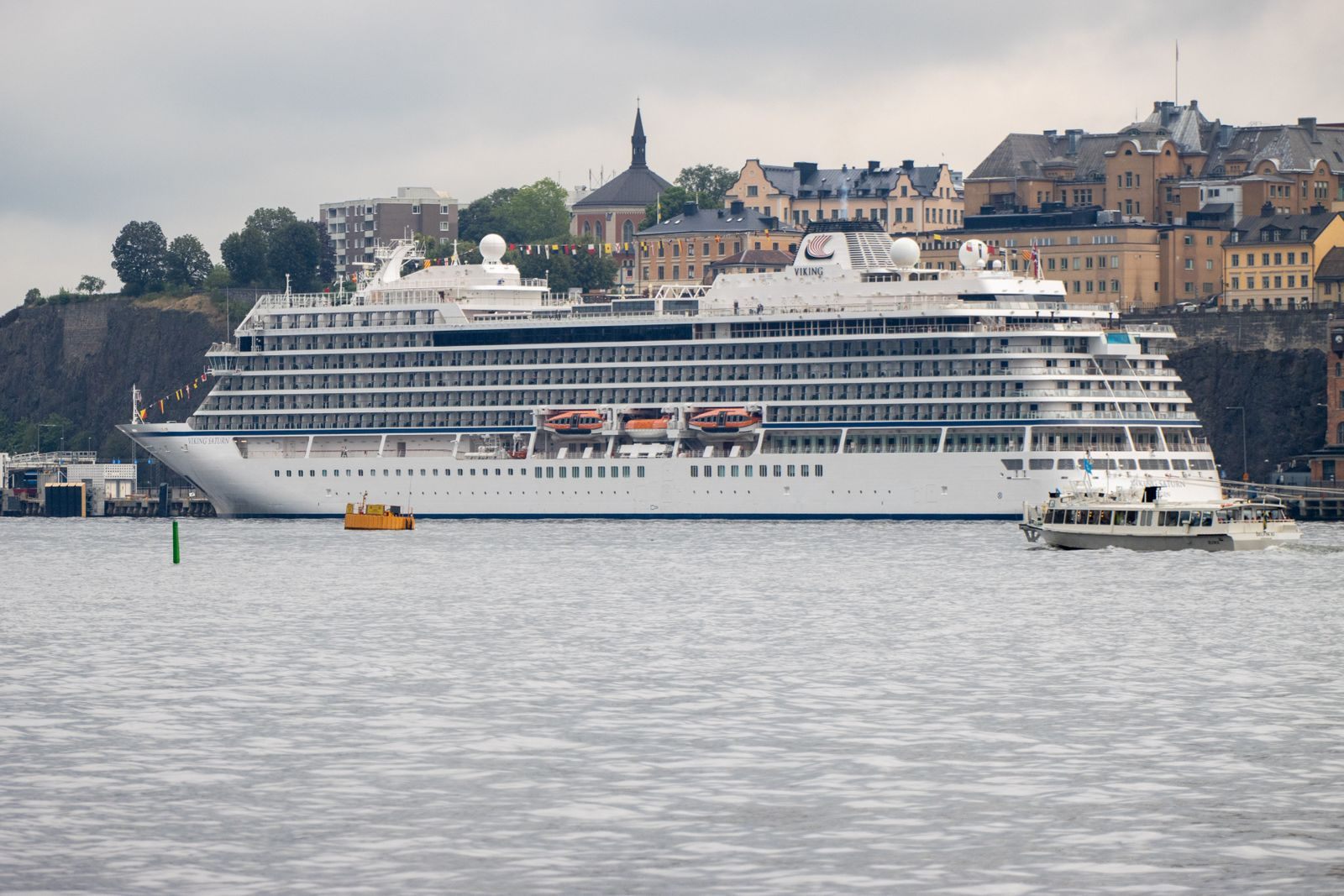 A cruise ship docked below the historic waterfront buildings of a European old town
