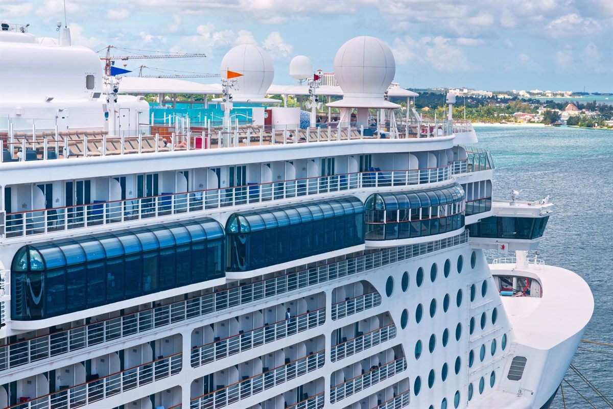 The side of a cruise ship berthed at a sunny island port